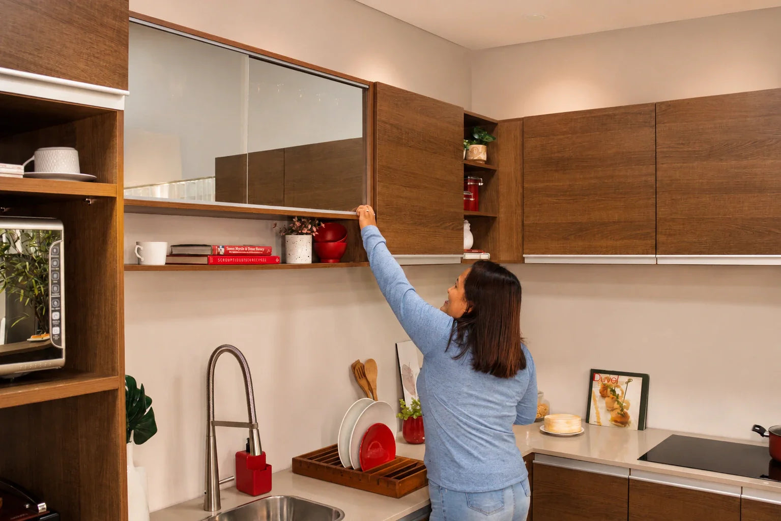 Mujer abriendo módulos altos de madera línea Glamy de Madesa que aprovechan la altura en una cocina chica.