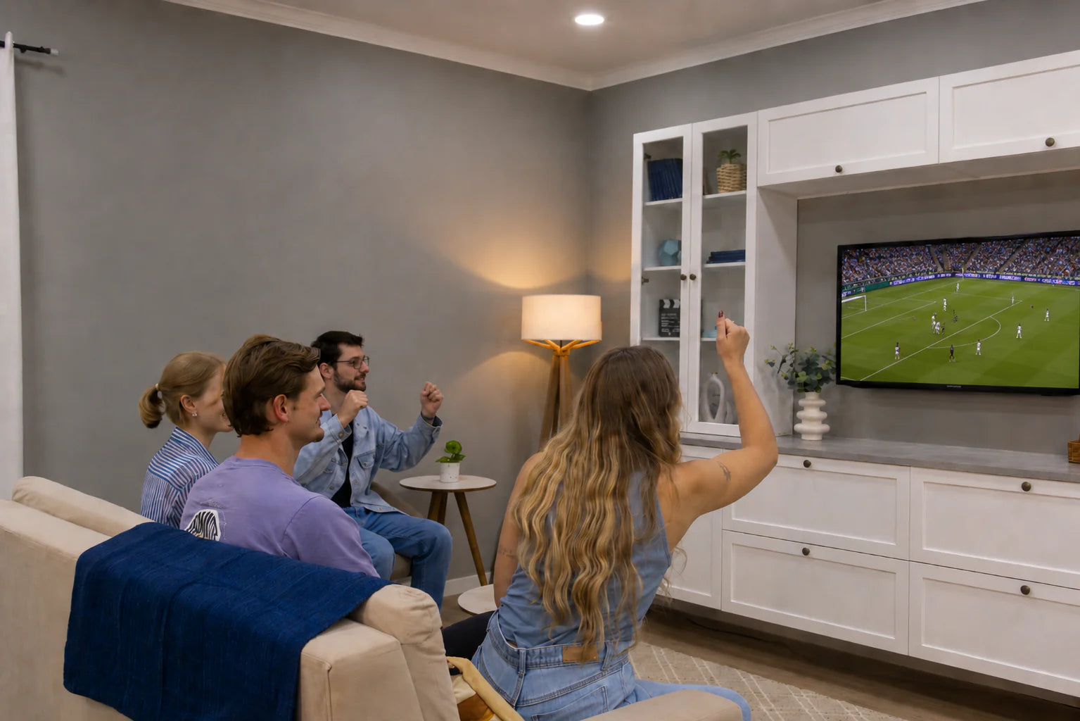 Amigos viendo los partidos en un living con rack con panel de TV blanco y estantes vitrina